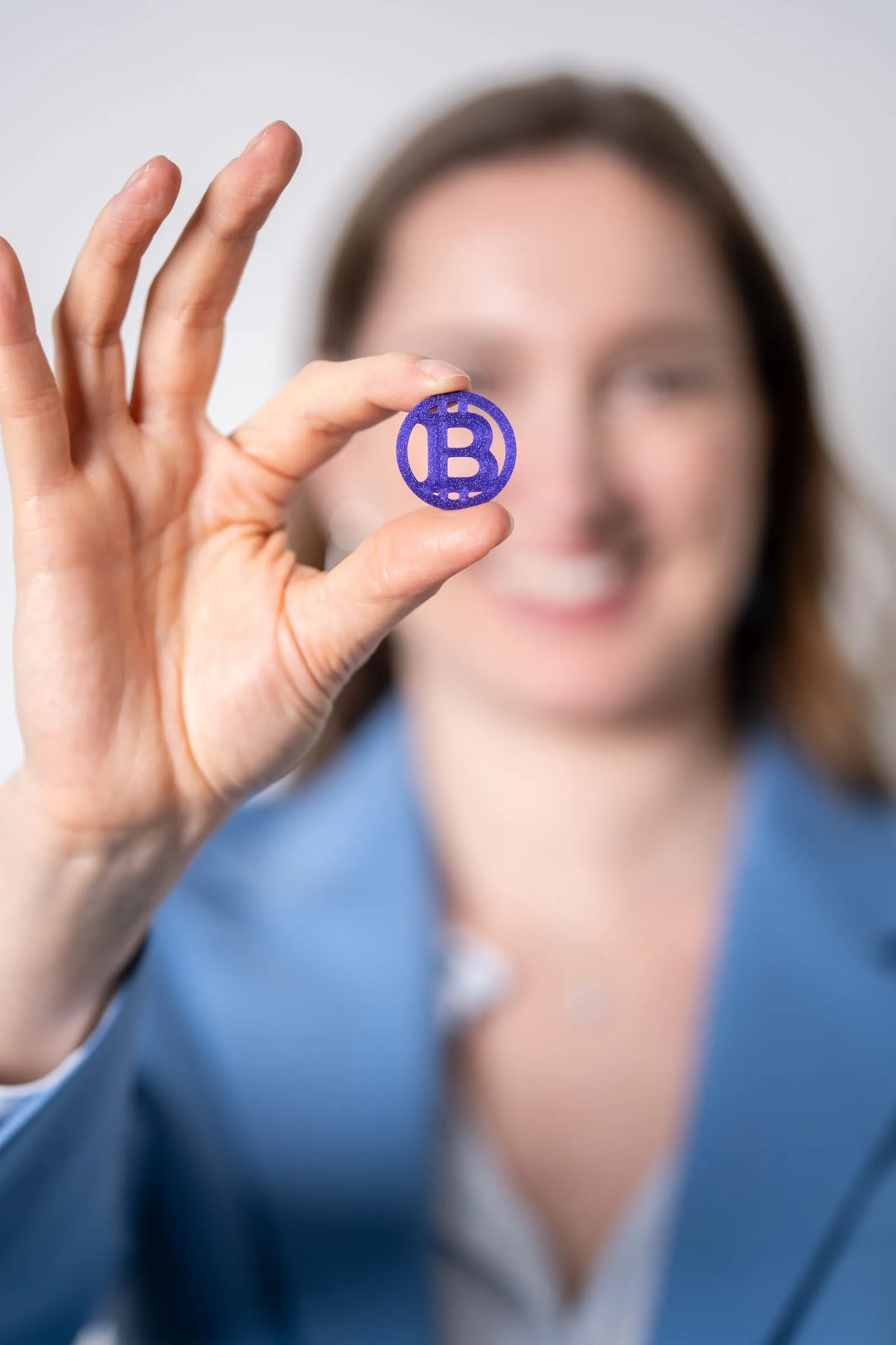 Lisa Tscherry hält eine violette Bitcoin-Münze in die Kamera